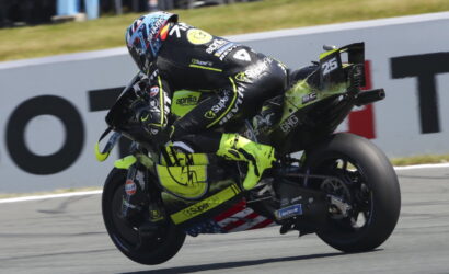 Motorcycle racer in a neon-yellow suit leans into a turn on a race track, bike number 25.