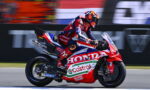 MotoGP rider in red-blue leathers on a Honda Castrol race bike speeding along a racetrack with a blurred background.