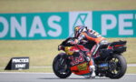 MotoGP rider in full leathers leaning into a turn on a race bike with Red Bull livery.