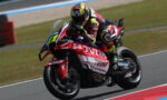 Moto racing rider on a red Honda sport bike, leaning into a corner on a racetrack.