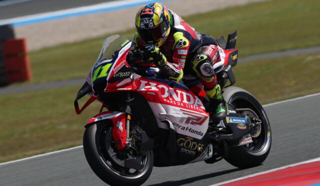 Moto racing rider on a red Honda sport bike, leaning into a corner on a racetrack.