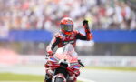 Racer on a red Lenovo motorcycle on the track, helmeted rider waving to the cheering crowd