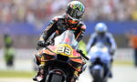 Motorcycle racer wearing a black and orange suit on an orange KTM bike with number 33, Red Bull livery, leaning into a turn.
