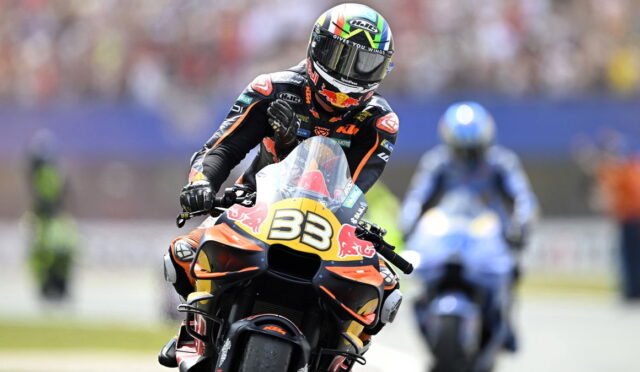 Motorcycle racer wearing a black and orange suit on an orange KTM bike with number 33, Red Bull livery, leaning into a turn.