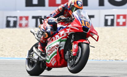 Moto racer in red-blue suit leaning into a turn on a red Honda bike with Costa branding, number 10 visible.