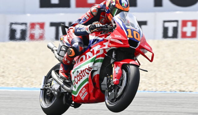 Moto racer in red-blue suit leaning into a turn on a red Honda bike with Costa branding, number 10 visible.