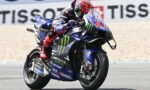 Moto racer on a blue Yamaha motorcycle, leaning into a turn with Monster Energy livery on a racetrack