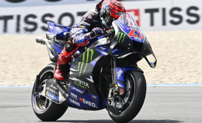 Moto racer on a blue Yamaha motorcycle, leaning into a turn with Monster Energy livery on a racetrack