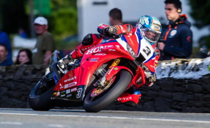 Motorcycle racer in red racing suit leaning into a turn on a red sport bike with number 3, during a race.