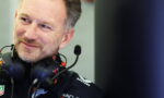 Close-up of a smiling man wearing a black racing headset with a microphone in front of him