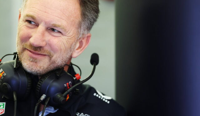 Close-up of a smiling man wearing a black racing headset with a microphone in front of him