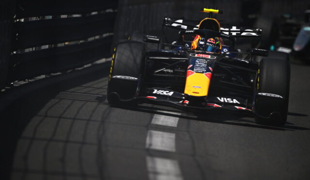 Red Bull Racing Formula 1 car speeding along a track beside barriers, driver in helmet visible.