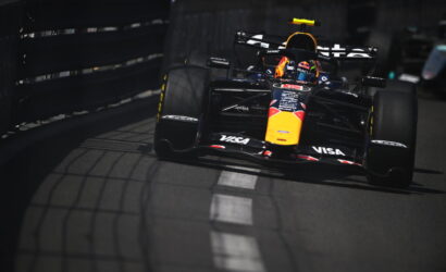 Red Bull Racing Formula 1 car on a street circuit, front view near the barrier with a helmeted driver in cockpit.