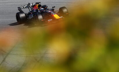 Red Bull Racing Formula 1 car on a race track, seen through blurred yellow foliage.