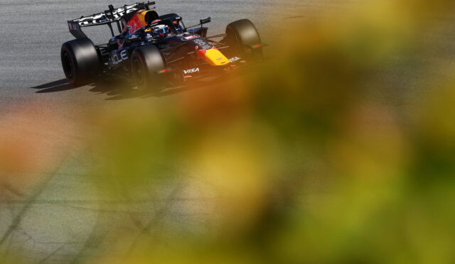 Red Bull Racing Formula 1 car on a race track, seen through blurred yellow foliage.