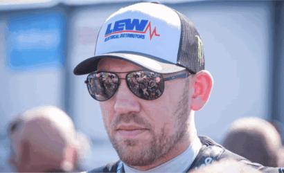 Man wearing a white and black trucker cap with the LEW Electrical Distributors logo and mirrored sunglasses; crowd reflected in the lenses.