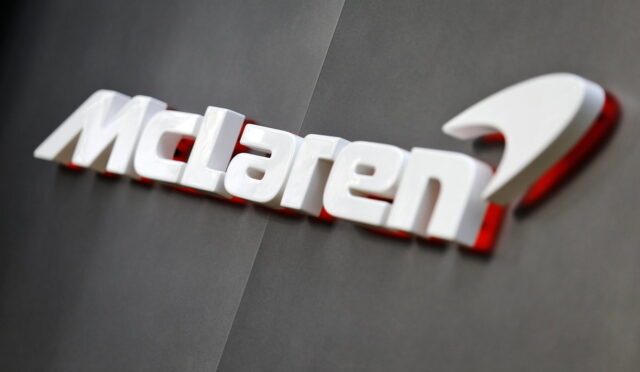McLaren logo in white lettering with a subtle red shadow on a dark gray wall