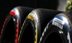 Close-up of three Pirelli racing tires arranged in a row, showcasing yellow Pirelli branding on the center tire.