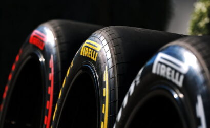Close-up of three Pirelli racing tires arranged in a row, showcasing yellow Pirelli branding on the center tire.