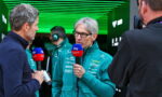 Team member in a teal jacket being interviewed, holding a Sky Sport microphone, in a green-lit garage/pit area.