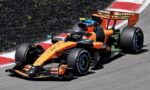 Orange McLaren Formula 1 car on a race track taking a corner at high speed.