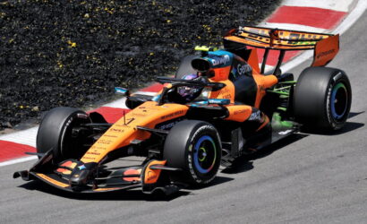 Orange McLaren Formula 1 car on a race track taking a corner at high speed.
