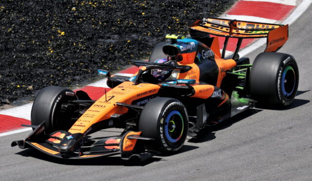 Orange McLaren Formula 1 car on a race track taking a corner at high speed.