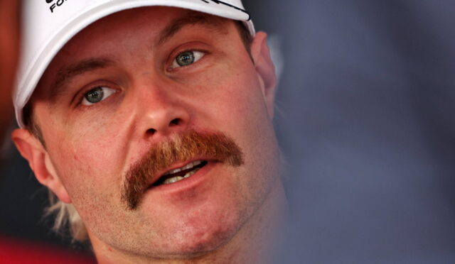 Close-up of a man with a red mustache wearing a white cap, looking slightly to the side.