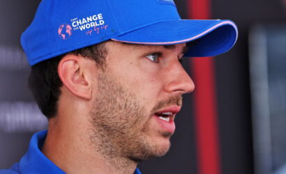 Side profile of a man wearing a blue cap with the 'Change the World' logo, speaking or listening.