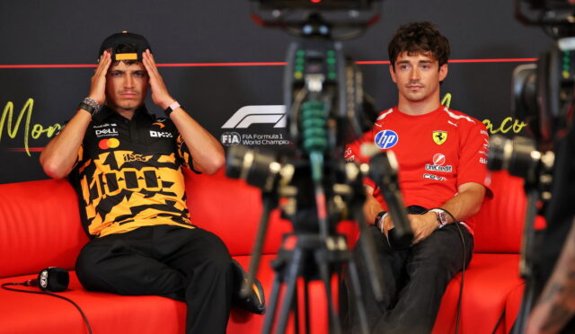Two Formula 1 drivers sit on a red couch for an interview, cameras in the foreground.