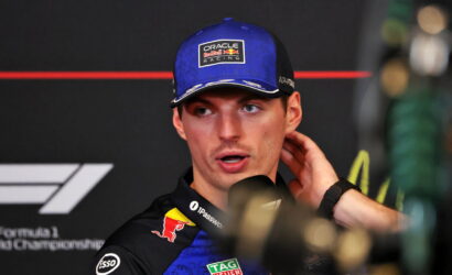 Close-up of a Formula 1 driver wearing a blue Oracle Red Bull Racing cap, being interviewed at a press event.