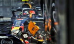 Close-up of a Red Bull Formula 1 car in a crash, with a damaged front wing and debris flying near the cockpit.