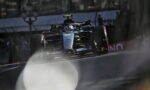 Mercedes-AMG F1 car racing on a track, front view with prominent Petronas branding and blue-green livery, action-packed moment on the straightaway