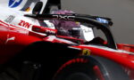 Close-up of a Formula 1 cockpit with a glittery purple helmet, red car body, and sponsor logos (HP, ZYN, Ferrari).