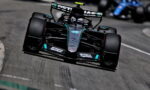 Mercedes-AMG Petronas Formula 1 car speeding around a track, front view in black and teal livery with sponsor logos visible