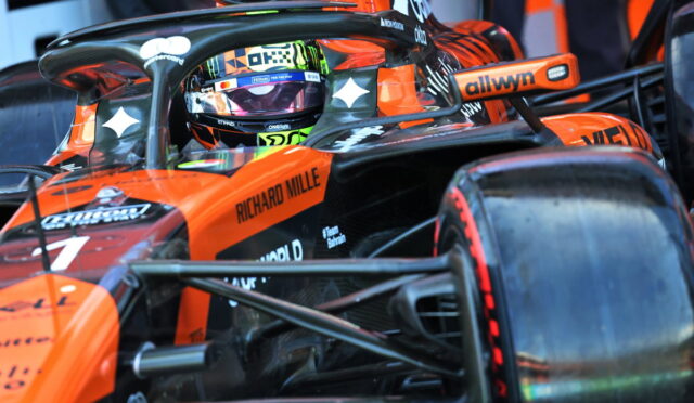 Orange Formula 1 car cockpit with driver wearing helmet, branding visible (Richard Mille, allwyn) and sponsor logos on the nose and halo bar.
