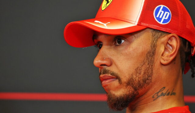 Man in profile wearing a red Ferrari cap and red shirt, neck tattoo visible on his left side, against a dark background.
