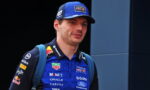 Portrait of a young man in Oracle Red Bull Racing blue cap and polo, with a blue backpack, looking off to the side.