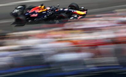 Red Bull Formula 1 car speeding on a race track with blurred grandstands in the background.