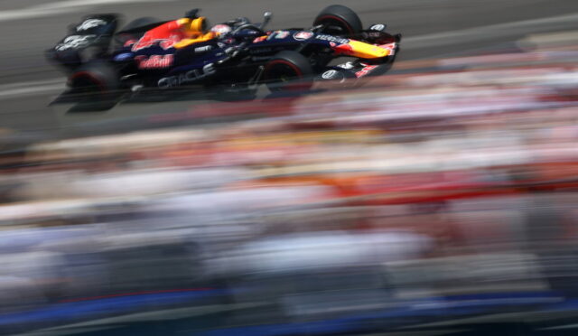 Red Bull Formula 1 car speeding on a race track with blurred grandstands in the background.