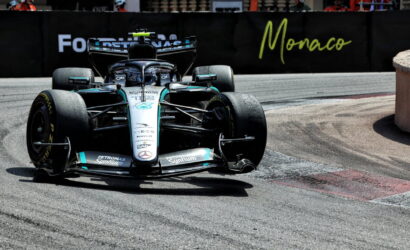 Mercedes F1 car from Mercedes-AMG Petronas speeds through a Monaco street circuit with barriers and spectators in the background