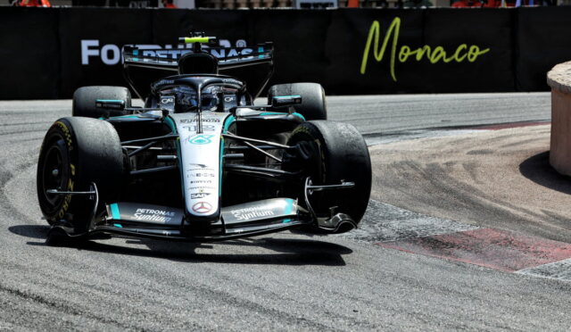 Mercedes F1 car from Mercedes-AMG Petronas speeds through a Monaco street circuit with barriers and spectators in the background