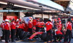 Ferrari Formula 1 pit crew in red uniforms working on a red race car in the pit lane, with CEVA Logistics signage overhead.