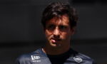 Close-up portrait of a dark-haired man in a navy sponsor jersey, looking off to the left, with Gulf and New Era logos visible on the chest.