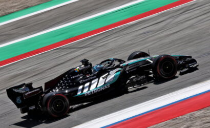 Mercedes-AMG Petronas F1 car speeding along a track with green and red run-off areas in the background.
