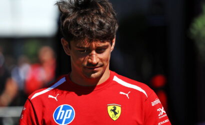 Young man in a red Ferrari team shirt looking down, with HP and Ferrari crest logos visible.
