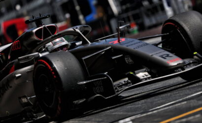 Formula 1 race car on track, close-up of front wing and tires, silver livery with sponsor logos visible