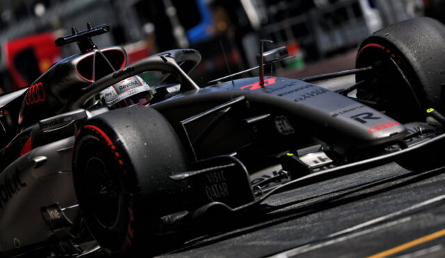 Formula 1 race car on track, close-up of front wing and tires, silver livery with sponsor logos visible