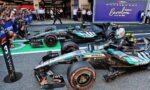 Mercedes Formula 1 cars lined up in the pit lane with a cheering crowd taking photos, a large Barcelona banner in the background.