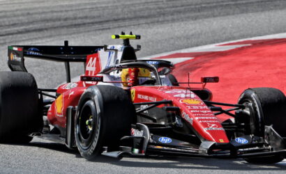 Ferrari Formula 1 car, number 44, rounding a track corner with sponsor logos visible (Shell, HP).